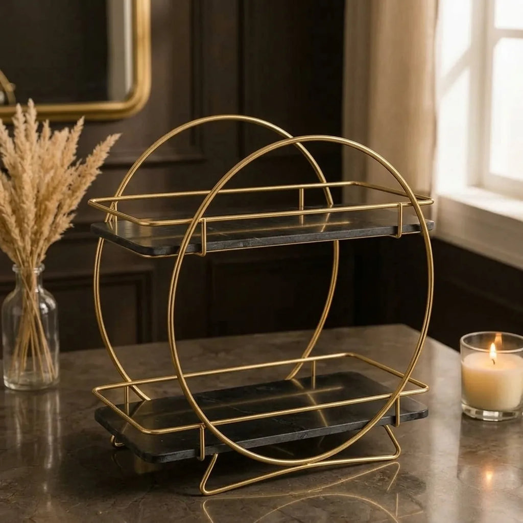 Round two-tier vanity organizer in Onyx — black marble shelves passing through a gold ring frame on splayed gold feet