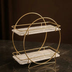 Angled view of the round two-tier organizer in Pearl showing the shelf overhang and the splayed gold feet